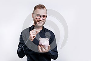 Smiling businessman using piggybank to save money