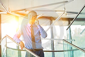 Smiling businessman using smartphone while standing at office