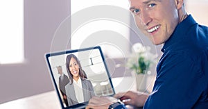 Smiling businessman video conferencing with colleague on laptop in office