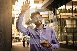 Smiling businessman walking trough street and say hi someo