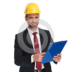 Smiling businessman wearing a protection helmet holds blue files