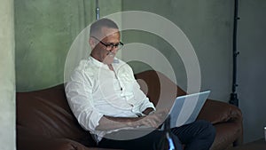 Smiling businessman working on laptop computer at home office. Male professional typing on laptop keyboard at office