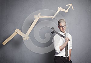 Smiling businessman with wrench and graph.