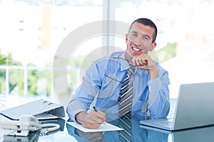 Smiling businessman writing notes