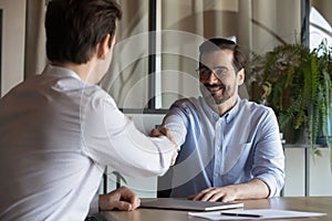 Smiling businessmen handshake closing deal at meeting