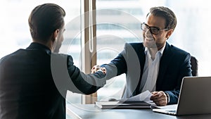 Smiling businessmen shake hands get acquainted in office photo