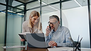 Smiling businesspeople collaborating in modern office. Businessman talking phone