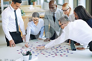 Smiling businesspeople solving a jigsaw puzzle in an office