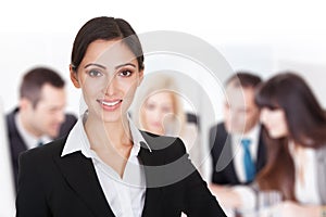 Smiling businesswoman against team discussing in boardroom