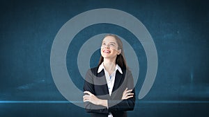 Smiling businesswoman with arms folded looking up at copyspace. Standing over blue background.