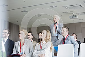 Smiling businesswoman asking questions during seminar