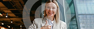 Smiling businesswoman communicating in sign language while looking at camera while sitting in cafe