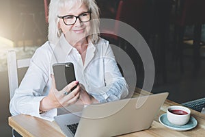 Smiling businesswoman dressed in white shirt is sitting at table