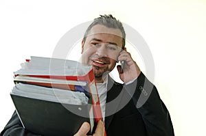 smiling businesswoman with folders in hand, talking on thel phon