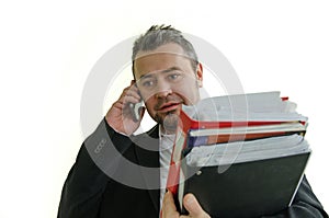 smiling businesswoman with folders in hand, talking on thel phon