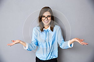 Smiling businesswoman in gesture of asking over gray background