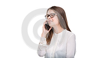 Smiling businesswoman in glasses talking on mobile phone. Beautiful young girl in white shirt on white isolated background talking