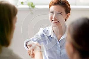 Smiling businesswoman greeting shaking hand client, new colleague, vacancy candidate