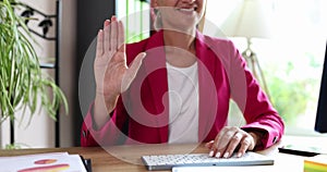 Smiling businesswoman greets waving at camera closeup
