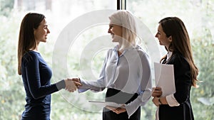 Smiling businesswoman handshake female employee in office