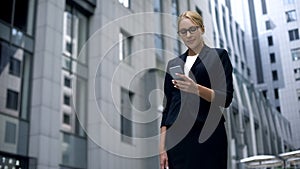 Smiling businesswoman happy to read message on smartphone with good news, salary