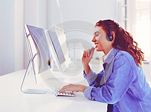Smiling businesswoman with headset using laptop at the desk in work