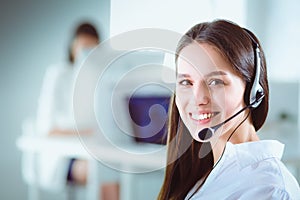 Smiling businesswoman or helpline operator with headset and computer at office