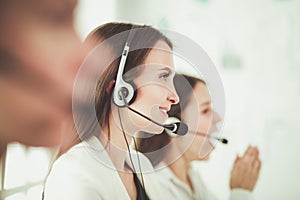 Smiling businesswoman or helpline operator with headset and computer at office