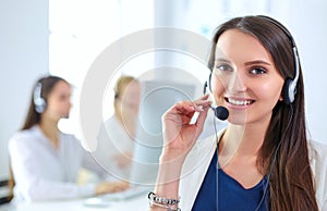 Smiling businesswoman or helpline operator with headset and computer at office