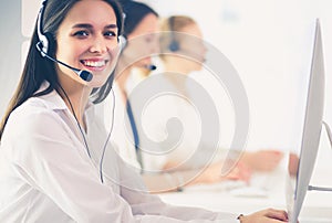 Smiling businesswoman or helpline operator with headset and computer at office