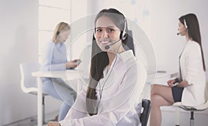 Smiling businesswoman or helpline operator with headset and computer at office