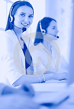 Smiling businesswoman or helpline operator with headset and computer at office