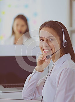 Smiling businesswoman or helpline operator with headset and computer at office