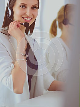 Smiling businesswoman or helpline operator with headset and computer at office