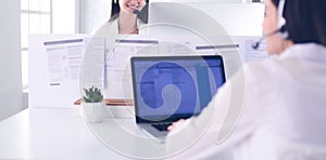 Smiling businesswoman or helpline operator with headset and computer at office