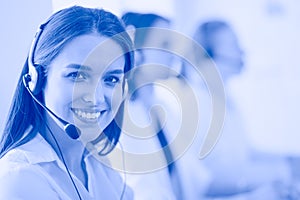 Smiling businesswoman or helpline operator with headset and computer at office