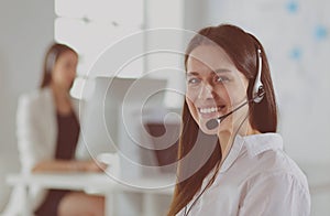 Smiling businesswoman or helpline operator with headset and computer at office