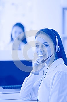 Smiling businesswoman or helpline operator with headset and computer at office