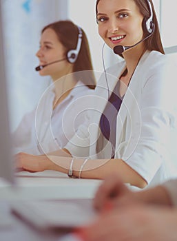 Smiling businesswoman or helpline operator with headset and computer at office