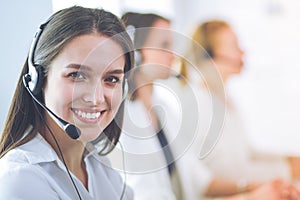 Smiling businesswoman or helpline operator with headset and computer at office