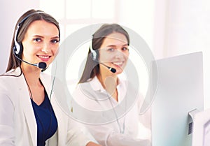 Smiling businesswoman or helpline operator with headset and computer at office