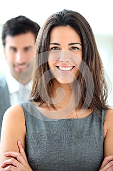 Smiling businesswoman and her colleague in the back