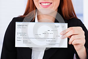 Smiling businesswoman holding cheque