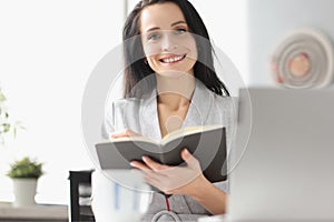 Smiling businesswoman holding diary with silver pen in hand