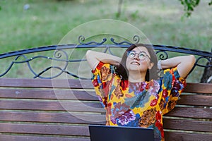 Smiling businesswoman with laptop enjoying relaxing in park after work
