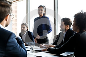 Smiling businesswoman lead team meeting with employees in office