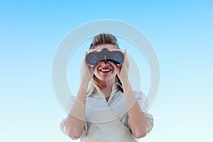 Smiling businesswoman looking through binoculars