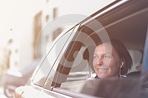 Smiling businesswoman looking out the window of company car