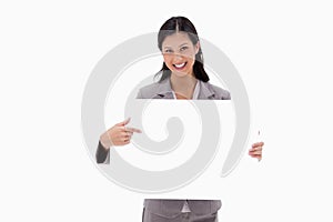 Smiling businesswoman pointing at blank sign board