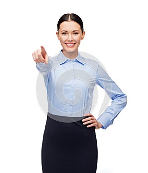 Smiling businesswoman pointing finger at you